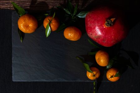 Still life of pomegranates and tangerines in the dark key. Composition of ingredients (fruits) for making fresh juice.の写真素材