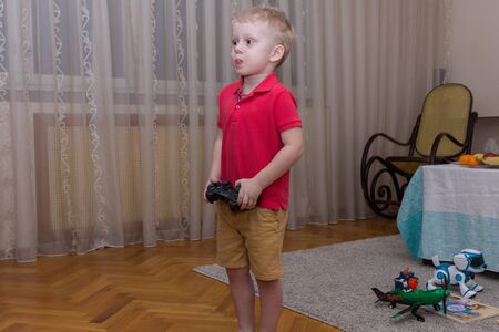 2019.02.09, Maloyaroslavets, Russia. Happy birthday party at home. A little boy playing computer game on TV, front view.のeditorial素材