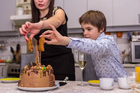 2019.02.09, Maloyaroslavets, Russia. Happy birthday party at home. boy helps mom remove cake decorations.のeditorial素材