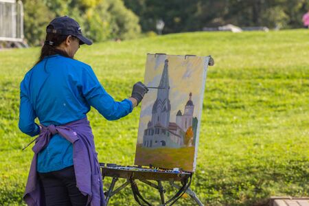 2019.09.01, Moscow, Russia. An artist painting an old church from nature in an autumn park.