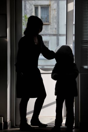 Silhouette of mom accompanying her son for a walkの写真素材
