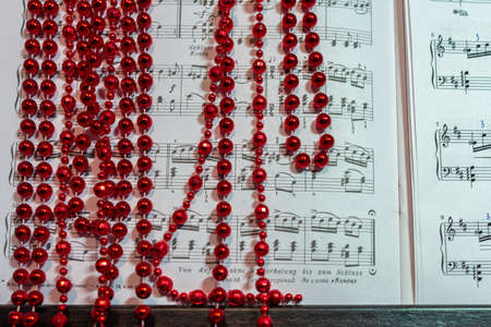 12/29/2018, Moscow, Russia. red beads (Christmas decoration) lie casually on the piano keyboard and...