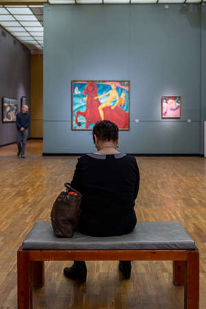 11.17.2017 Moscow, Russia. A woman sits in the Tretyakov Gallery opposite the painting of Petrov-Vodkin "Bathing the Red Horse".のeditorial素材