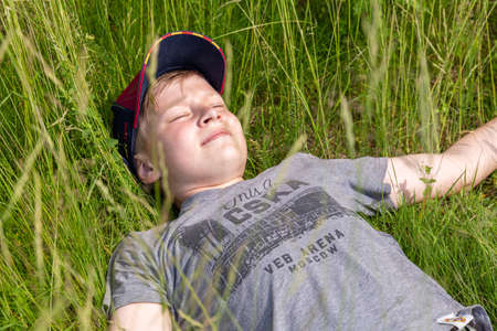 06.24.2020, Maloyaroslavets. Russia. Ateenage boy wearing sports style lying on the field of cereal.のeditorial素材