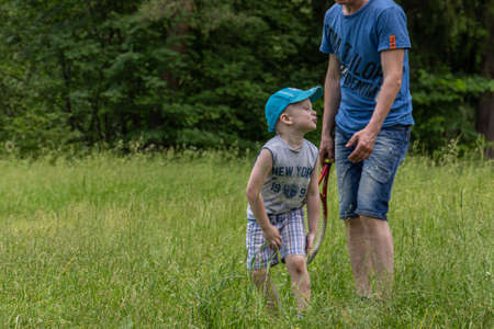 06.24.2020, Maloyaroslavets. Russia. A little boy and his father playing big tennis on the meadow in the forest.のeditorial素材