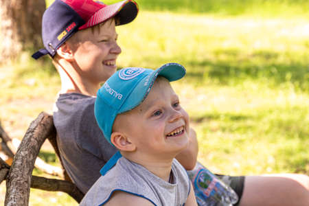 06.24.2020, Maloyaroslavets. Russia. Two smiling brothers sitting on the bench in the park. Boys...