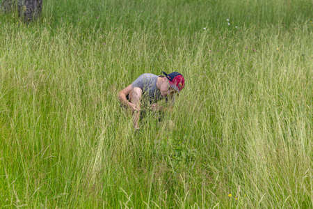 06.24.2020, Maloyaroslavets. Russia. A teenager boy walking across tall grass around a field.