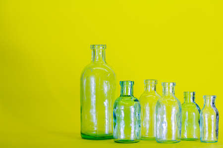 six empty glass bottles of different sizes on the yellow background. Concept of medicine and science.の写真素材
