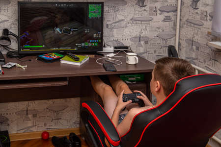 20.09.2020, Maloyaroslavets, Russia. A teen boy sitting in the armchair by the table and gaming.
