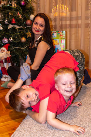 31.12.2018, Maloyaroslavets, Russia. Two little brothers and mother having fun at home. Happy emotions and New Year mood.のeditorial素材