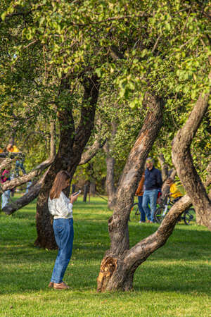 09/27/2020, Moscow, Russia. A young beautiful woman standing in the apple tree garden.のeditorial素材