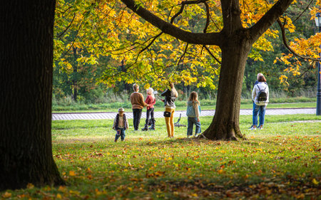 09/27/2020, Moscow, Russia. a group of tourists are photographed against the background of maple trees in the autumn park. People walking in the falling park.のeditorial素材