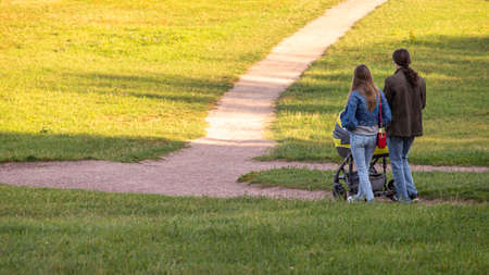 Young parents and their baby walking in the summer park. People on the nature.