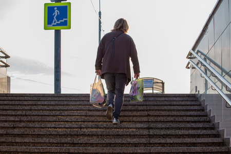 09/16/2020, Moscow, Russia. woman carries bags of groceries and climbs the stairsのeditorial素材