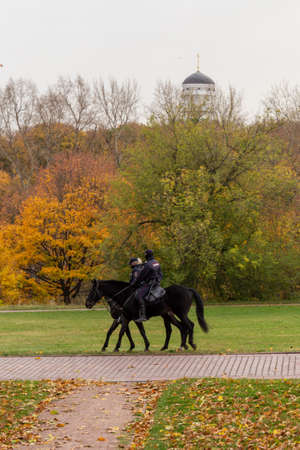 11.10.2020, Moscow, Russia. Police officers riding horse on background of falling trees. Travel around Moscow.のeditorial素材