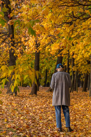13.10.2020, Moscow, Russia. A young woman texting in the autumn garden.のeditorial素材