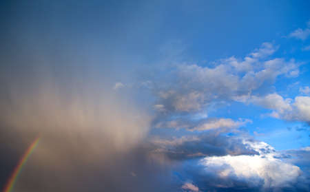 stormy sky with a rainbow on blue skyの写真素材