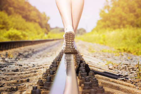 female legs in sneakers on the rail of the railwayの写真素材