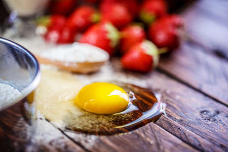 flour, egg strawberry on a wooden board
