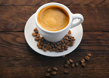 white cup of coffee grains on a wooden background