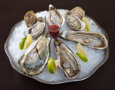 A Belon oyster on ice with sauce and lemon.  Decorating a dish of French and European cuisine....