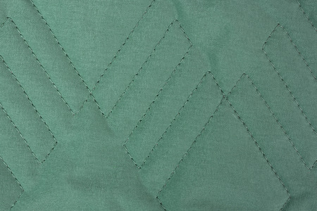 Green quilted fabric texture with geometric patternの写真素材