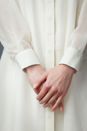 Young women's beautiful hands with graceful fingers on elegance white silk dress. Closeupの写真素材