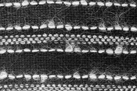 Black hand weaving matting tweed fabric texture with white stripes. Closeup horizontal fragment