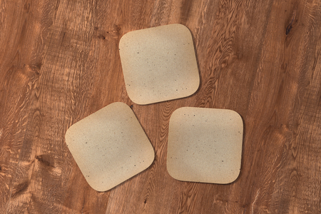 Three square vintage coasters on wood background. 3d illustrationの写真素材
