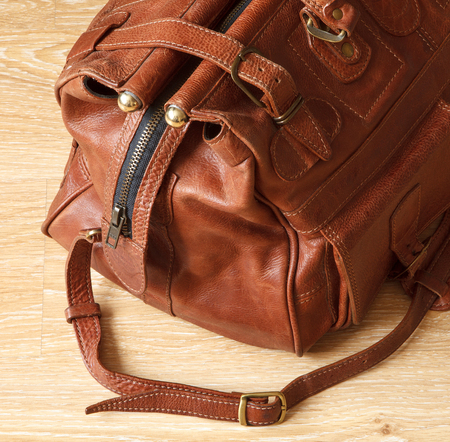Brown leather travel bag or valise on wooden floor.の写真素材