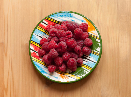 Raspberry on plate on wooden background. View above