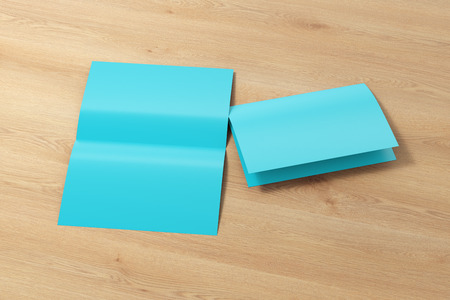 Blank cyan open and folded half-folded flyer leaflet on wooden background.  3d illustration