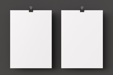 Two blank paper posters hanging on binder clips on black wall background. 3d illustrationの写真素材