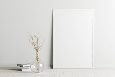 Blank vertical poster frame mock up standing on white floor next to white wall with vase and books.