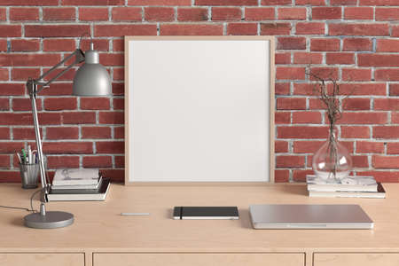 Square poster frame mockup on the wooden table of home studio workspace with red brick wall. Front...