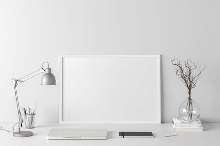Horizontal poster frame mockup on the BBB table of home studio workspace with white wall. Front...