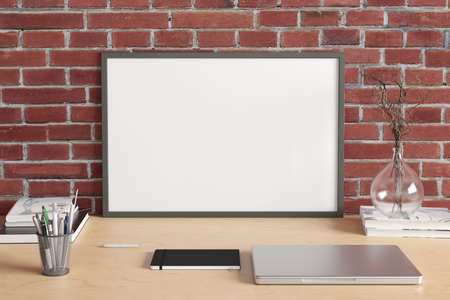 Horizontal poster frame mockup on the wooden table of home studio workspace with red brick wall....
