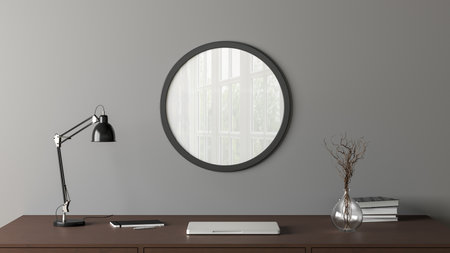 Dark wooden round poster frame mock up on the gray wall of home studio workspace. Front view. 3d illustrationの写真素材
