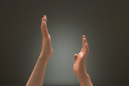 Women's palms up in a dance gesture on the gray backgroundの写真素材