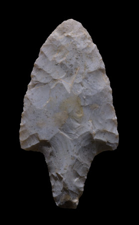 Neolithic flint arrowhead on black background
