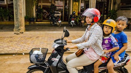 SIEM REAP, CAMBODIA - NOVEMBER 13, 2017: Three riders: Surprised Asian little boys, kids with mother on the scooter motorbike moped motorcycle. Copy space and text here. Concept of dangerous ridingのeditorial素材