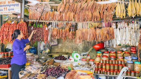 SIEM REAP, CAMBODIA - NOVEMBER 24, 2017:  asian woman - seller. The traditional Asian market with food. Sale a variety of dried seafood on the counterのeditorial素材