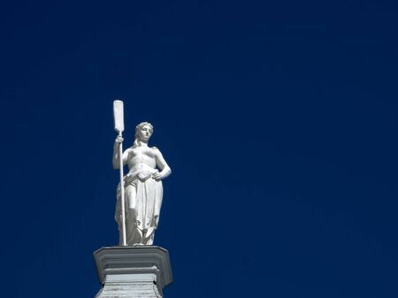 ST. PETERSBURG, RUSSIA - JULY 11, 2018: statue of a woman with a paddle, allegory of Navigation, roof Botsogo house . Statue on the blue background. Copy space for you design and textのeditorial素材