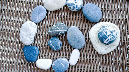 Sea stones laid out in the form of a circle. Spa stones, sea beach and wicker furnitureの写真素材