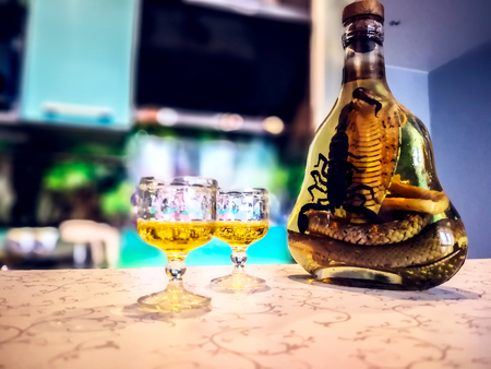Asian Local Bottle Whiskey and Liquor with Snakes and Scorpions, cambodia. medicinal liquor:  Poisonous animals.  Small wine glasses with liquid, bubbles and alcohol. beautiful background of kitchenの写真素材