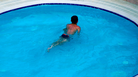 A man swimming slowly in a swimming pool on a hot sunny day.  Man swimming Stay at a resort in the...