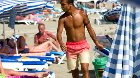 KONAKLI, ALANYA, TURKEY - 06 JULY 2018: Handsome and muscular man on beach. Summer vacation, holidays, relax. Having fun and joy concept. Many tourists, Deck chairs, umbrellas, loungers on background.のeditorial素材