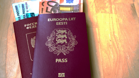 Passports on the wooden background. Citizenship of Estonia and Russia. Citizenship of European Union (EU) and Russian Federation. Top view. Copy space design. Rubles and Euro banknotes. Toned imageの写真素材