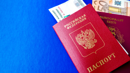 Passports on the blue background. Citizenship of Estonia and Russia. Citizenship of European Union (EU) and Russian Federation. Top view. Copy space for design. Rubles and Euro banknotes.の写真素材