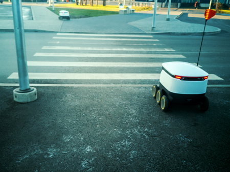 Two moving delivery robots on the street. crossing the road with a pedestrian crossing. cyber-couriers are already cruising the sidewalks in Estonia (Tallinn) are cruising the sidewalksの写真素材